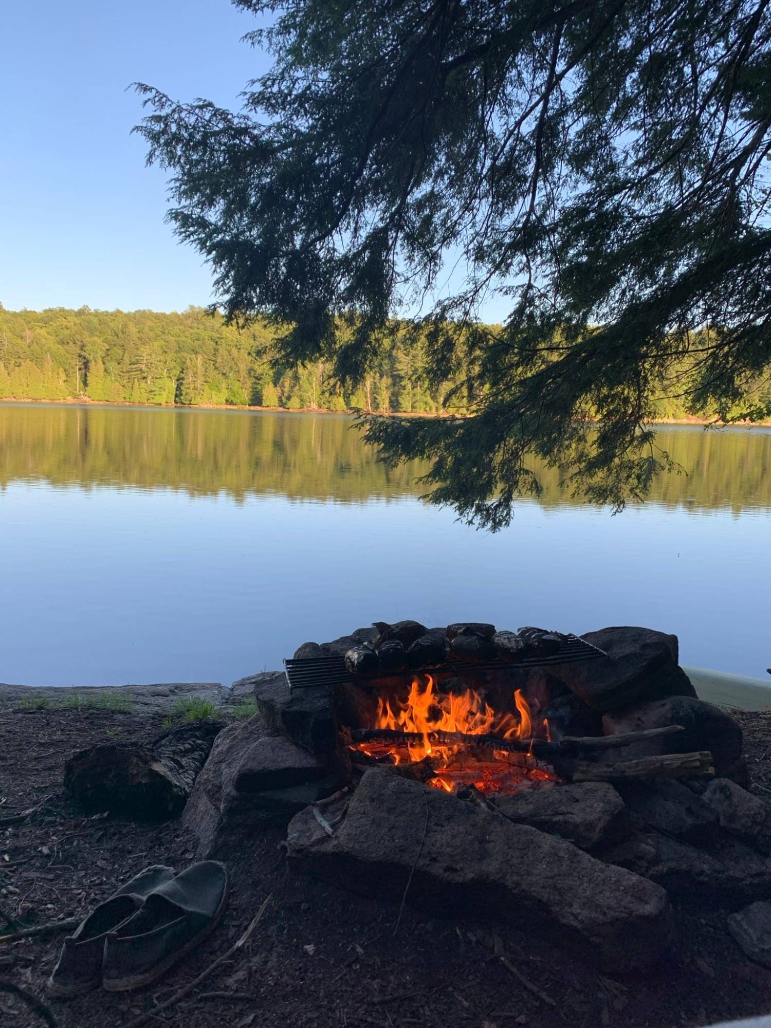 Campfire with a cooking grill at a lakeside backcountry campsite