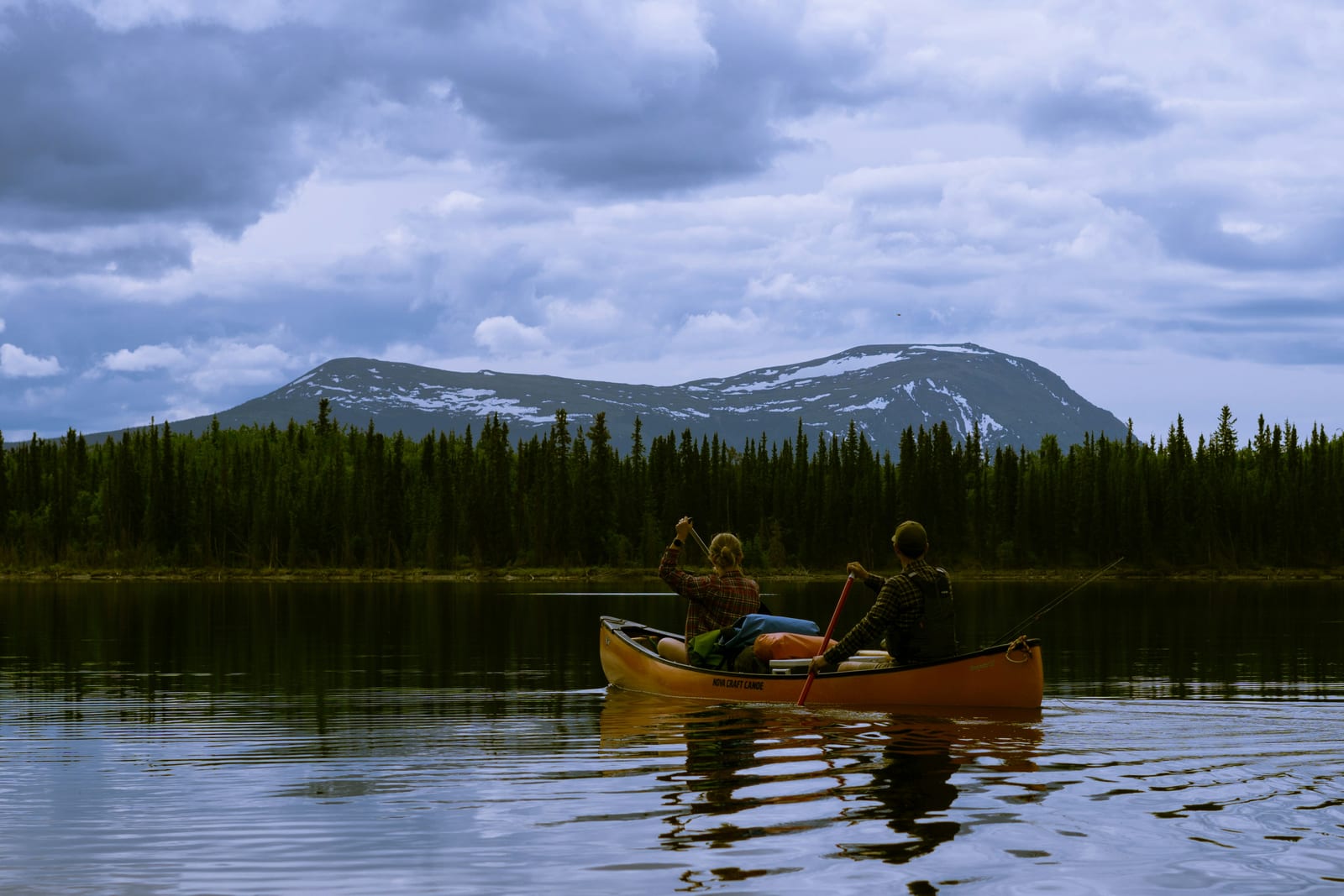 Canoe on a lake surrounded by mountains and forest